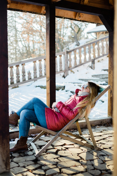 年轻女子喜欢在一个阳光明媚的冬日坐在外面的椅子上图片下载