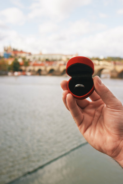 一个男人拿着一个红盒子和订婚戒指在查尔斯桥前面。布拉格，捷克共和国。胶片效果，作者对照片的处理图片下载