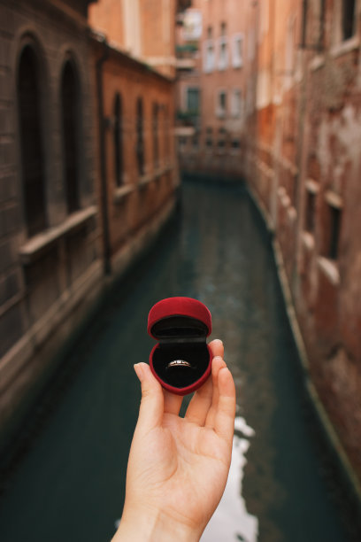 女人拿着红盒子与订婚戒指前威尼斯运河。在意大利威尼斯求婚。胶片效果，作者对照片的处理图片下载