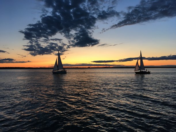 在海港浪漫美丽的黄昏，帆船在平静的海面上航行图片下载
