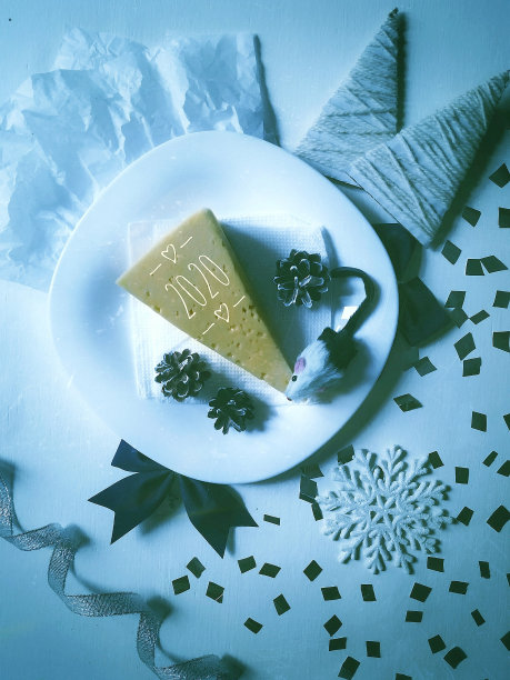 一只小老鼠在除夕夜吃白色盘子里的奶酪图片下载