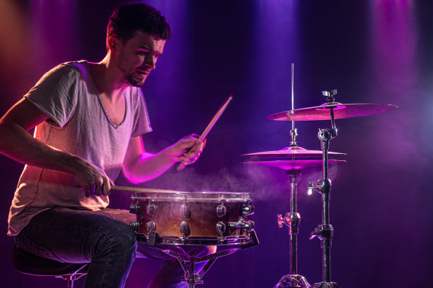 鼓手打鼓。美丽的蓝色和红色背景，与光线。美丽的特效烟雾和灯光。演奏乐器的过程特写照片。图片下载