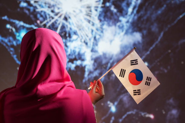 一名穆斯林妇女在晚上的烟花表演中戴着围巾举着韩国国旗。图片下载