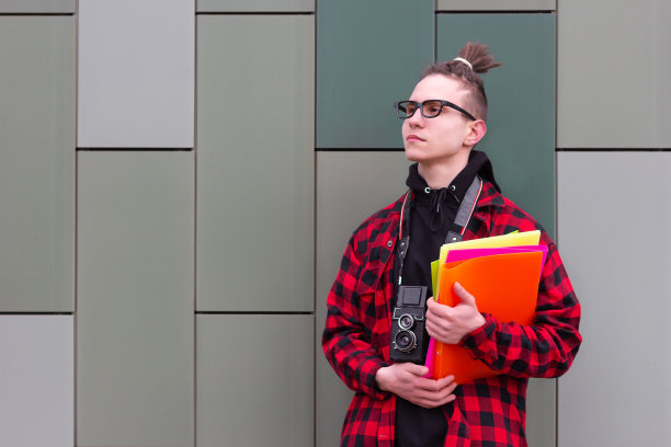 学生摄影师拿着书向一边看图片下载