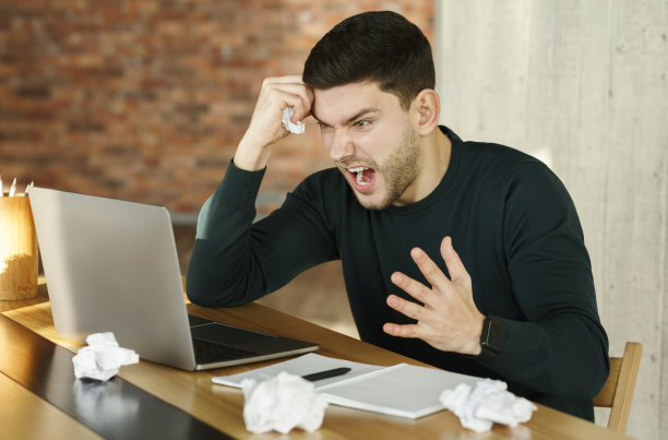 一名愤怒的商人坐在现代办公室里大喊着把纸弄皱图片下载