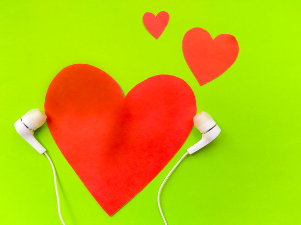 可爱的红色心形听音乐耳机在绿色的背景。图片下载
