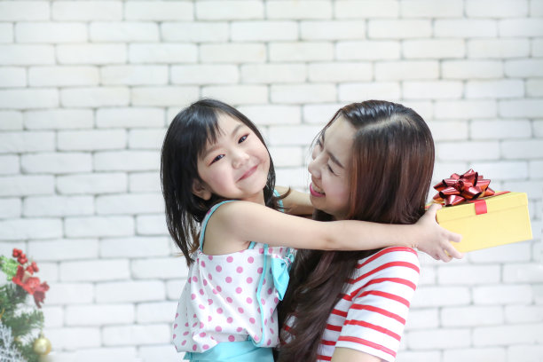 圣诞快乐，节日快乐或者新年快乐。妈妈给孩子们礼物。可爱的女孩给他心爱的妈妈一个礼物。新年的装饰在客厅。圣诞快乐的一天。图片下载