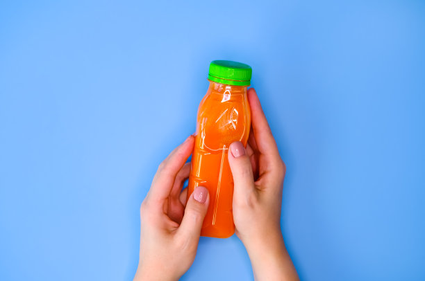 蓝色背景的女人手里拿着一瓶胡萝卜汁。平的风格。图片下载
