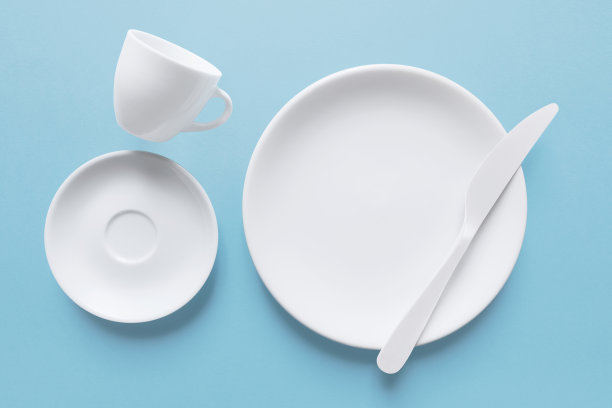 特写:白色咖啡杯和配有刀的盘子图片下载