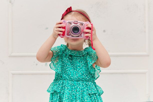 一个微笑着的小女孩拿着一个即时照相机在她的面前。影棚拍摄图片下载