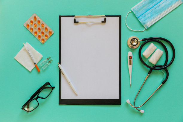 医生的桌面视图。听诊器，药片，眼镜和彩色背景的笔记本。图片下载