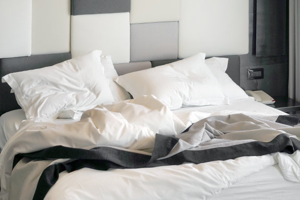 使用后的酒店床铺：脏枕头和毯子的房间图片下载