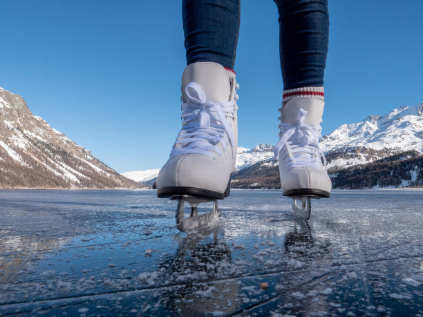 日落时分，在结冰的湖面上穿着溜冰鞋的双脚图片下载