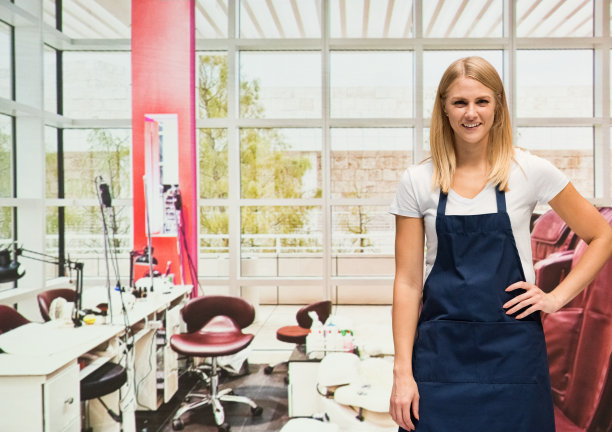 白人年轻女人穿着围裙站在美甲沙龙图片下载