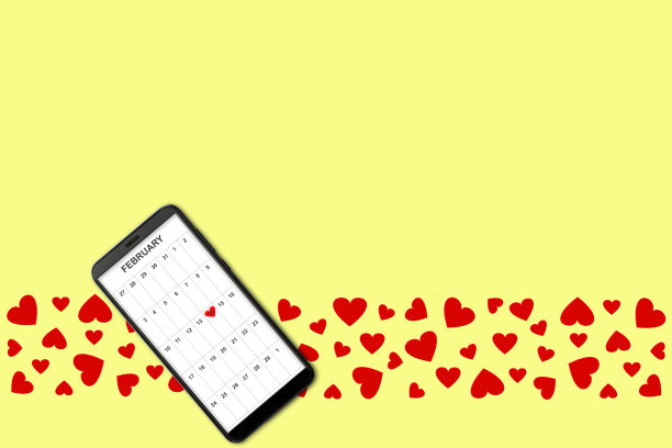 情人节概念，在黄色背景孤立红纸心和智能手机屏幕上的日历图片下载