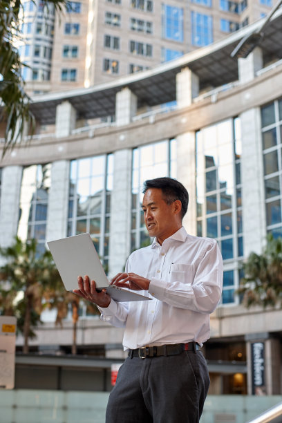 澳大利亚商人站在城市里用笔记本电脑工作图片下载