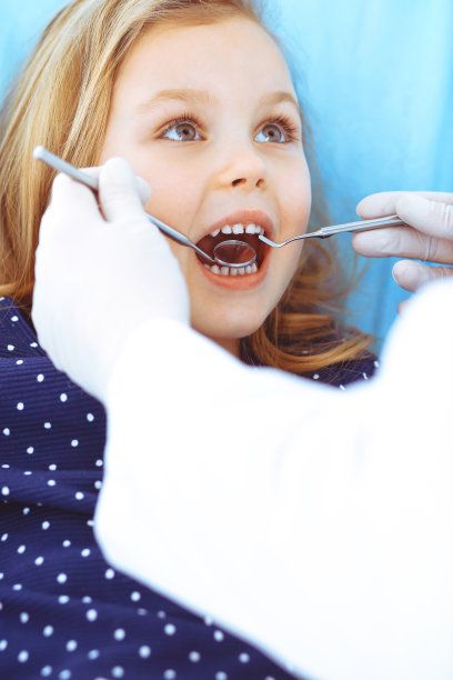 小女孩张大嘴巴坐在牙科椅上接受医生的口腔检查。拜访牙医的办公室。医学概念。健美的照片图片下载