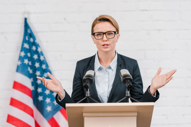 戴着眼镜的漂亮扬声器在靠近麦克风说话时打手势图片下载