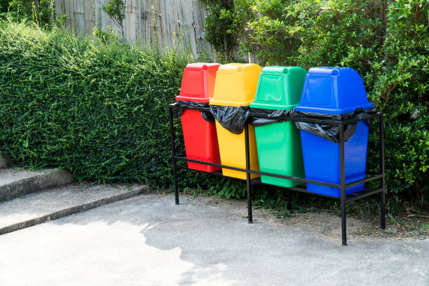 五颜六色的垃圾桶或垃圾桶在花园的背景。街道和楼梯旁的公园里有一排排五颜六色的塑料垃圾桶图片下载