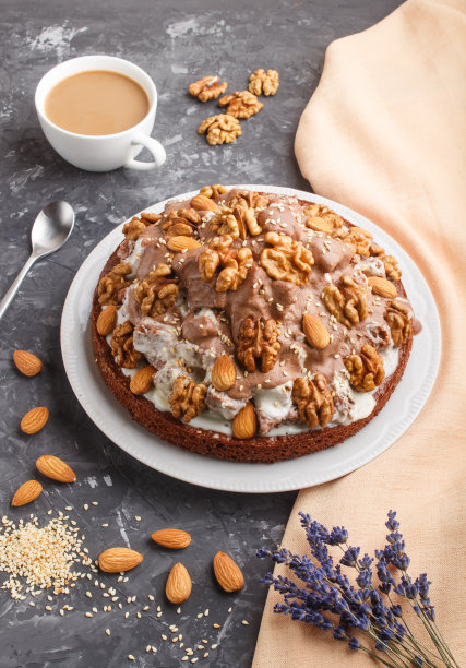 用牛奶奶油，可可，杏仁，榛子做的自制蛋糕，在黑色的混凝土背景下，用橙色的织物和一杯咖啡。侧视图，特写。图片下载