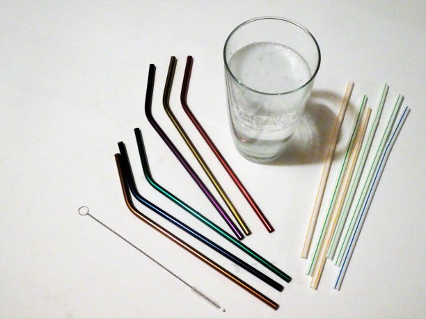 不锈钢吸管和清洁刷旁边的饮料在一个玻璃和塑料吸管-可重复使用和洗涤与一次性和塑料图片下载