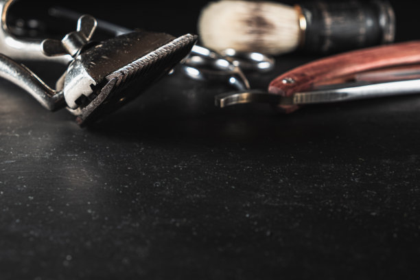黑色背景上的老式理发店设备。专业美发工具。剪刀，手动理发器，剃须刀，剃须刷。本空间图片下载