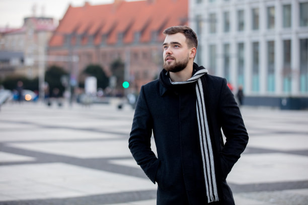 戴着围巾穿着外套的帅哥走在城市街道上图片下载