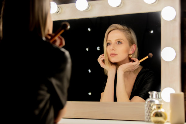 漂亮的金发女人用刷子靠近化妆镜图片下载