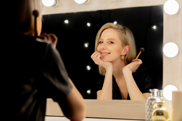 漂亮的金发女人用刷子靠近化妆镜图片下载