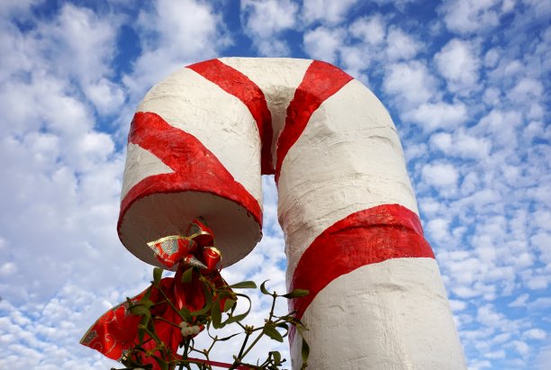 在美丽多云的蓝天下，用槲寄生树枝雕刻的大圣诞糖果手杖图片下载