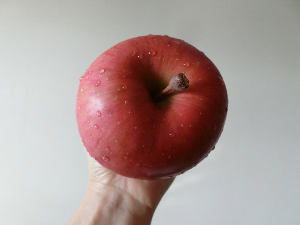 女手上有一个成熟的苹果，上面有水滴图片下载