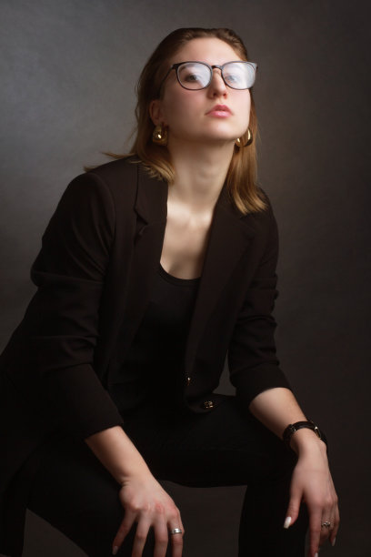 照相馆里一个棕色头发的女孩的肖像，背景是黑色的，穿着黑色的商务夹克。短头发。图片下载