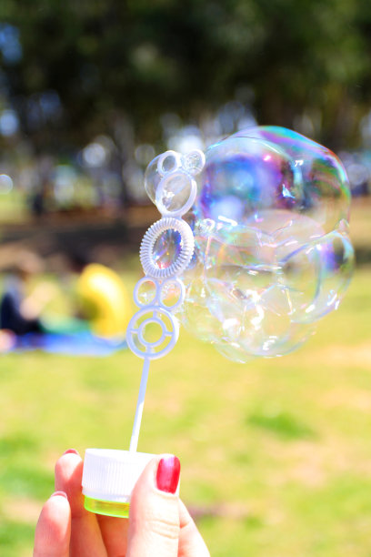 女人拿着魔杖在绿色背景上吹泡泡图片下载