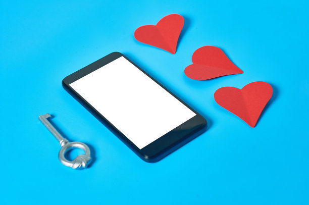 黑色智能手机与孤立的白色屏幕文本，图片，照片和其他图形附近的纸心和古董钥匙在蓝色的桌子。秘密或禁忌的爱的概念。空间的文本图片下载