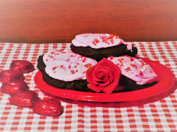 巧克力软糖饼干，粉红色的糖霜和点缀，心糖果在一边，红白桌布。图片下载
