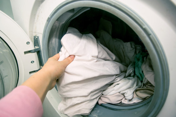 女人的手装载亚麻到洗衣机库存照片素材图片