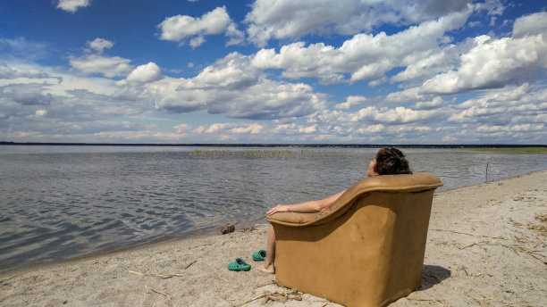 一个女人坐在扶手椅上，看着湖面图片下载
