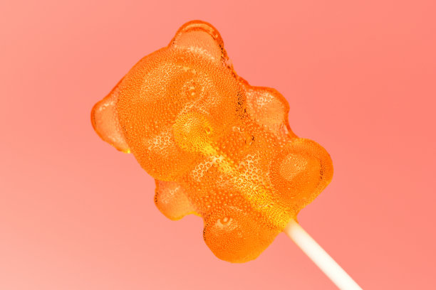 糖棒棒糖。一个棒棒糖焦糖在一个粉红色背景熊的形状的棒子上的特写图片下载