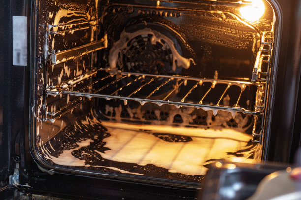 清除烤箱内的污垢。白色泡沫能溶解污垢。图片下载