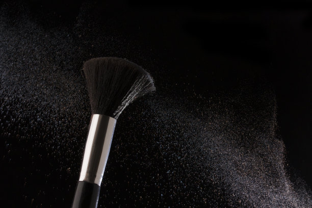 化妆刷在黑色背景与蓝色粉末近距离图片下载