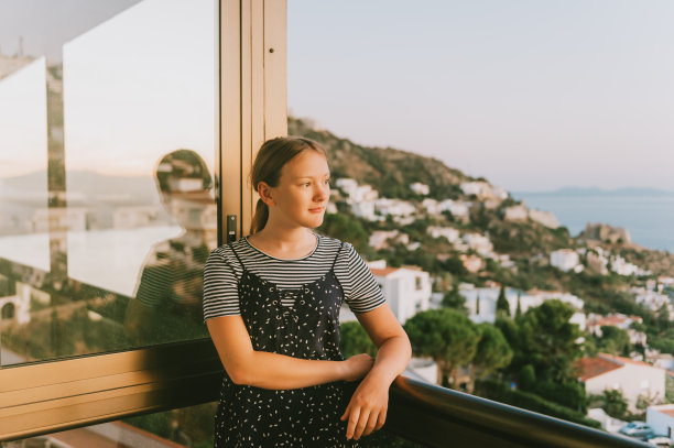 年轻的女孩在阳台上欣赏美丽的风景，暑假在海边，家人带着孩子旅行图片下载