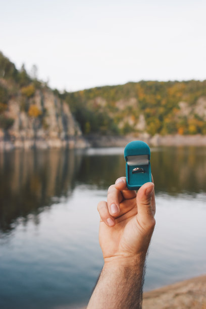 男人拿着一个带着订婚戒指的蓝色盒子前面是美丽的风景。捷克共和国兹维科夫城堡的求婚。胶片效果，作者对照片的处理图片下载