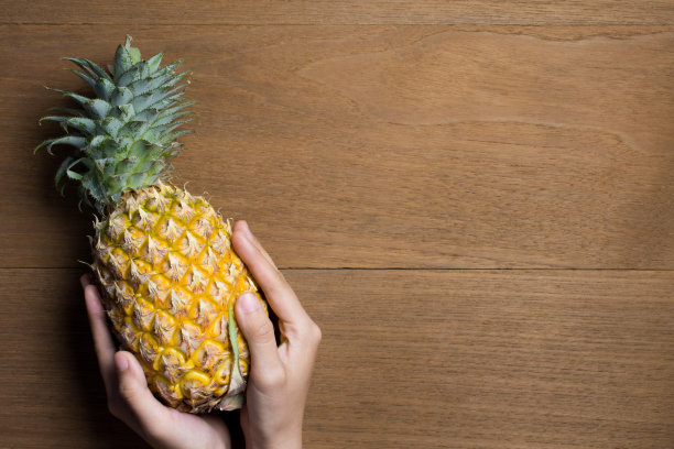 熟透的菠萝配上各种姿势的女人手牵着木头背景。图片下载