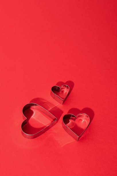 在右上角有三个心形的金属模板，红色的背景和情人节的复制空间图片下载