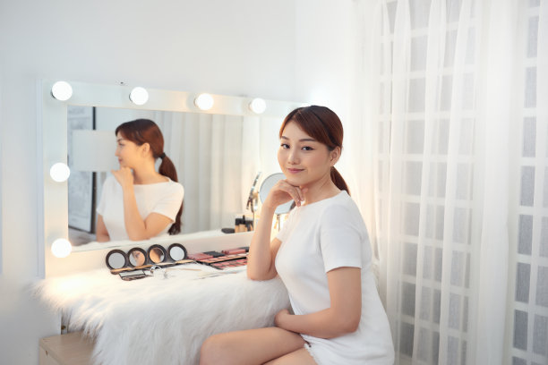 快乐的年轻亚洲女人坐在梳妆台后图片下载