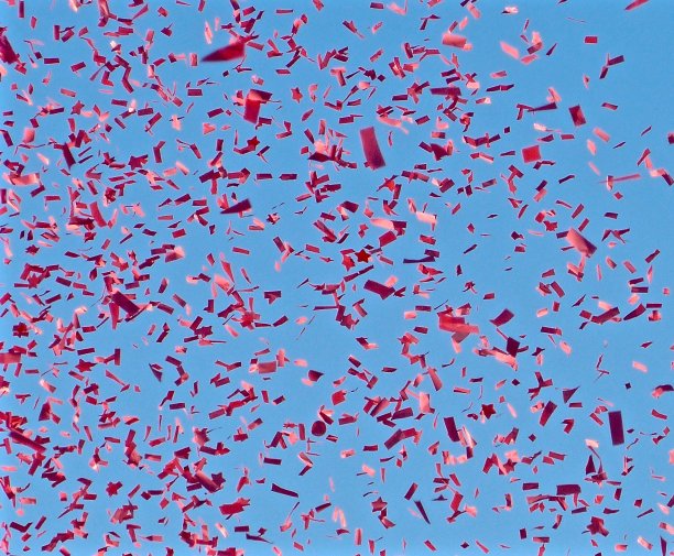 在晴朗的蓝天下，红色的五彩纸屑在空中飞舞图片下载