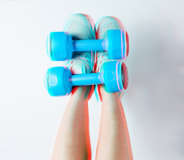 穿着运动鞋的女性腿拿着白色背景上的蓝色塑料哑铃。故障的效果。健身极简主义图片下载