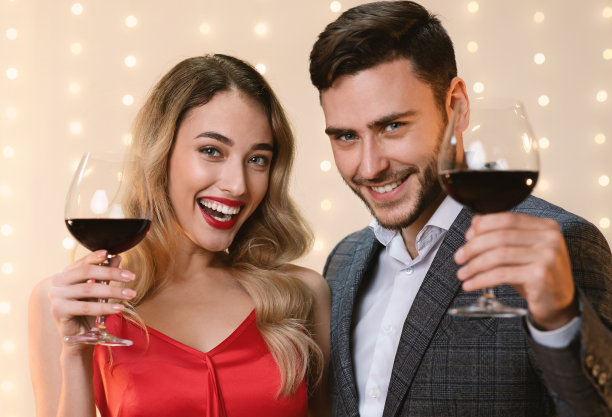 快乐的情侣拿着酒杯和红酒，庆祝情人节图片下载