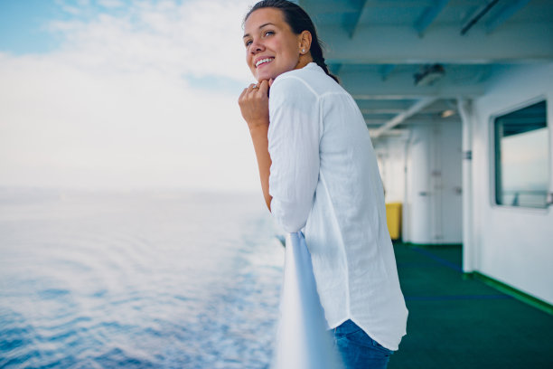 迷人的年轻女人在船甲板上靠在栅栏上的照片图片下载
