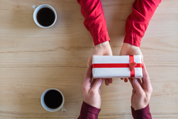 情人节。女人和男人在餐厅庆祝的特写。男朋友给女朋友送小盒子礼物。爱情,浪漫,日期。平躺图片下载